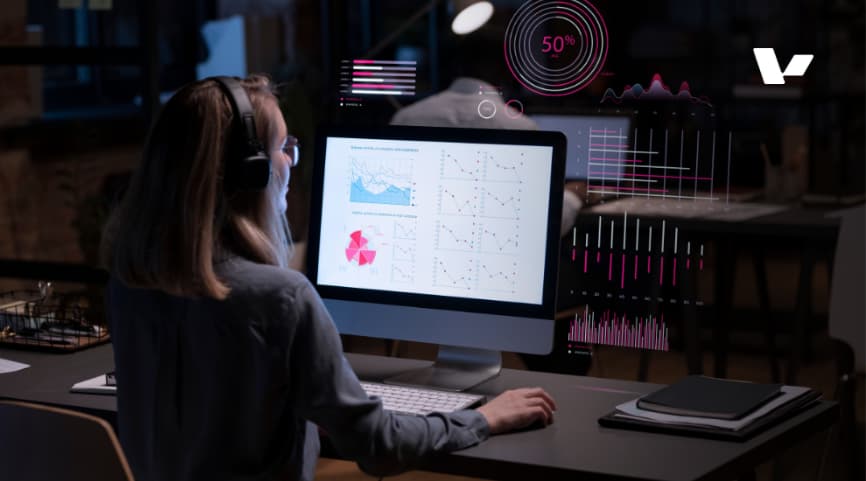 A person analyzing data visualizations on a computer screen, with dynamic graphs and charts displayed in front of them, representing data-driven decision-making and AI analytics.
